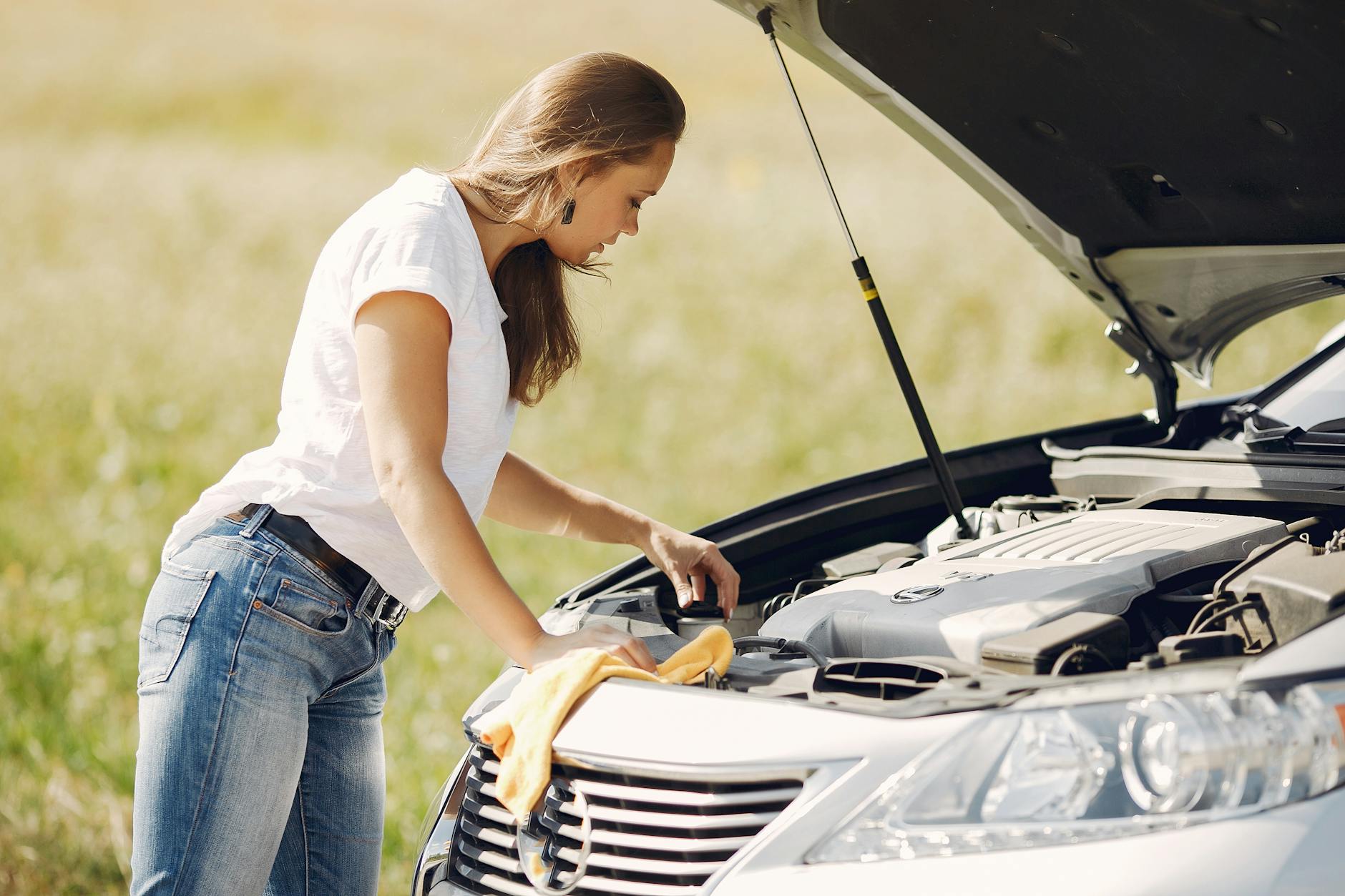 Kobieta sprawdza silnik Renault Captur na polnej drodze latem Kobieta sprawdza silnik Renault Captur na polnej drodze latem
