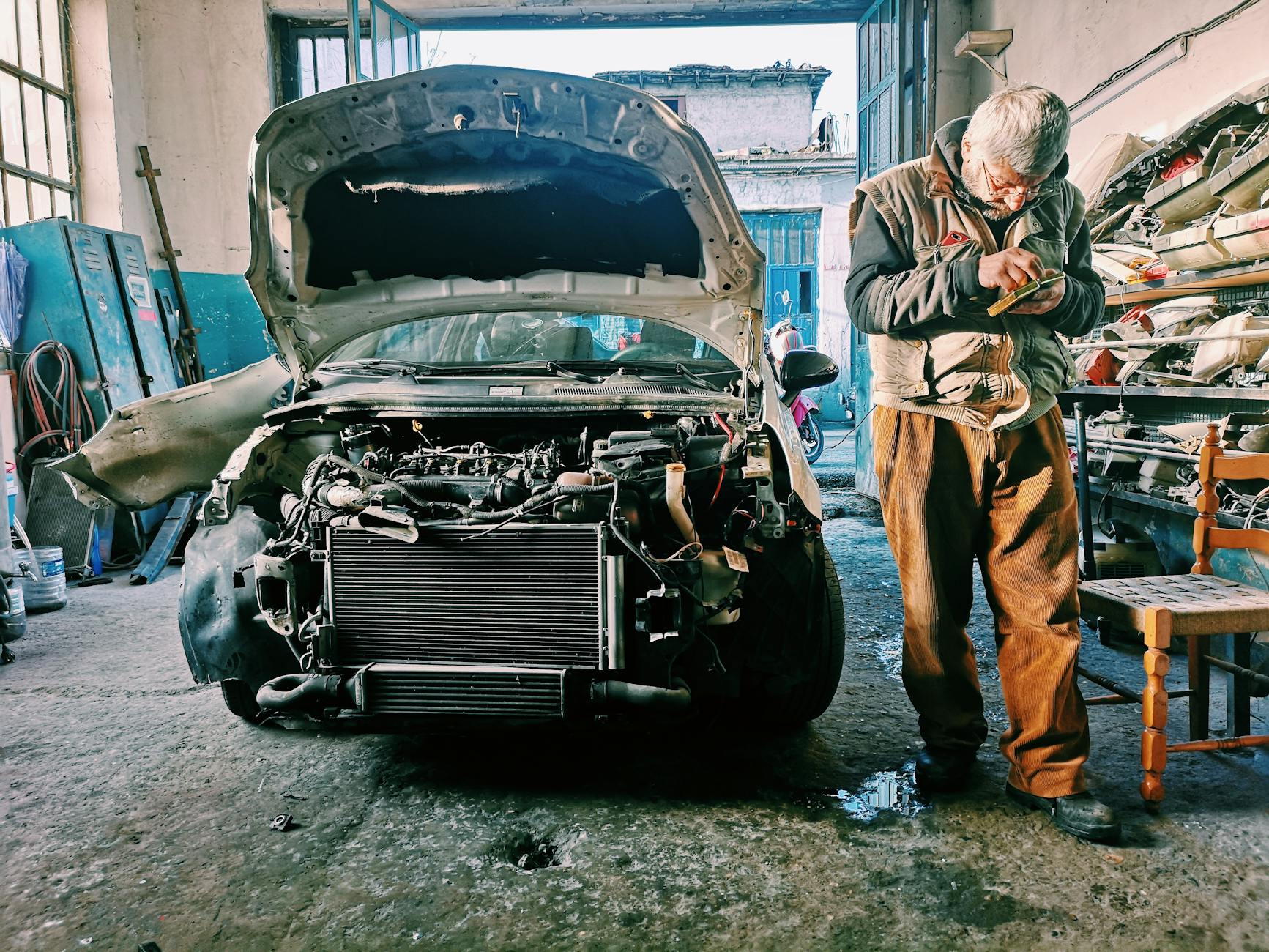 Mechanik naprawia samochód w warsztacie przy otwartej masce silnika