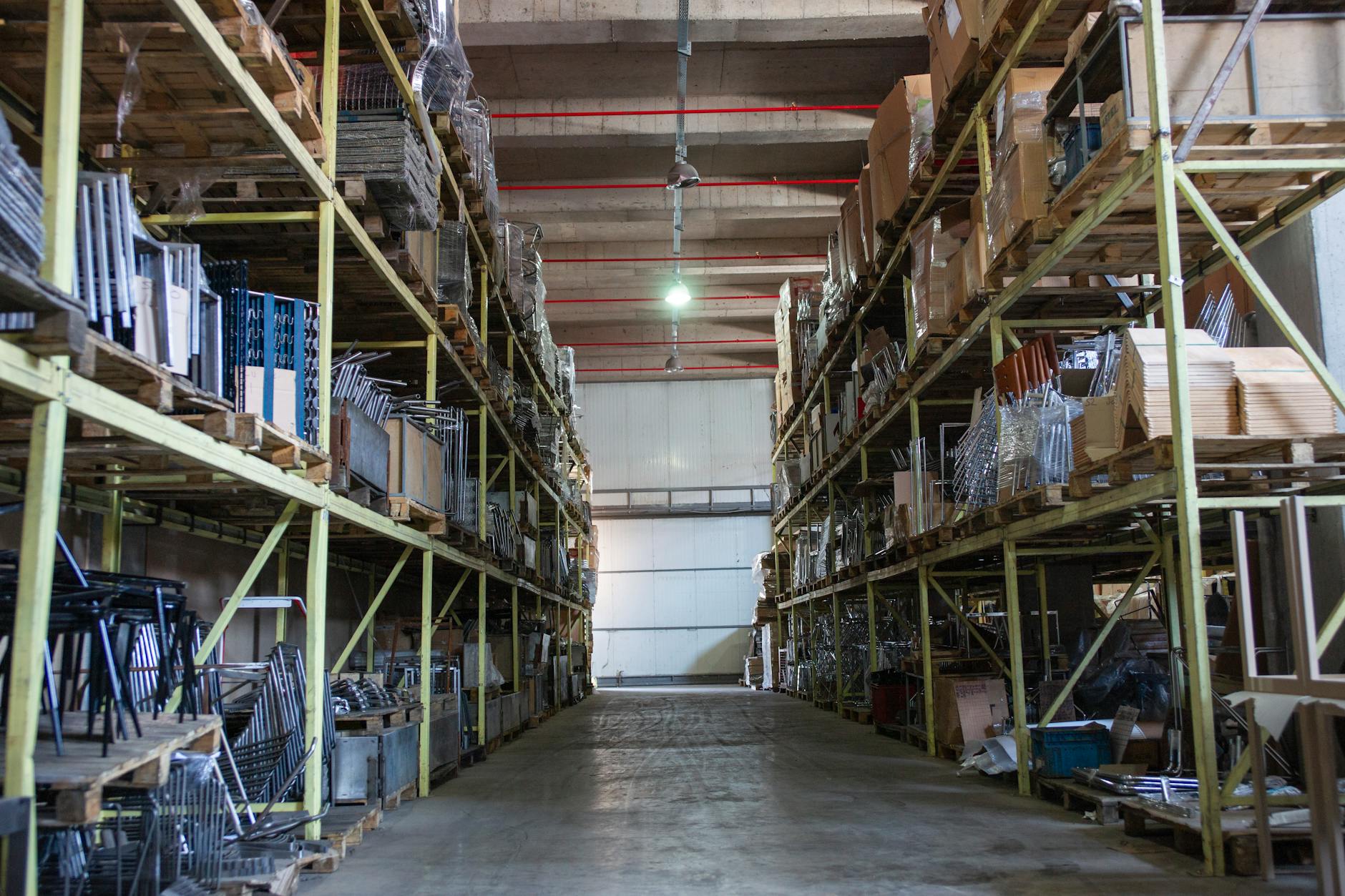 Szeroki korytarz w magazynie e-commerce z wysokimi regałami metalowymi