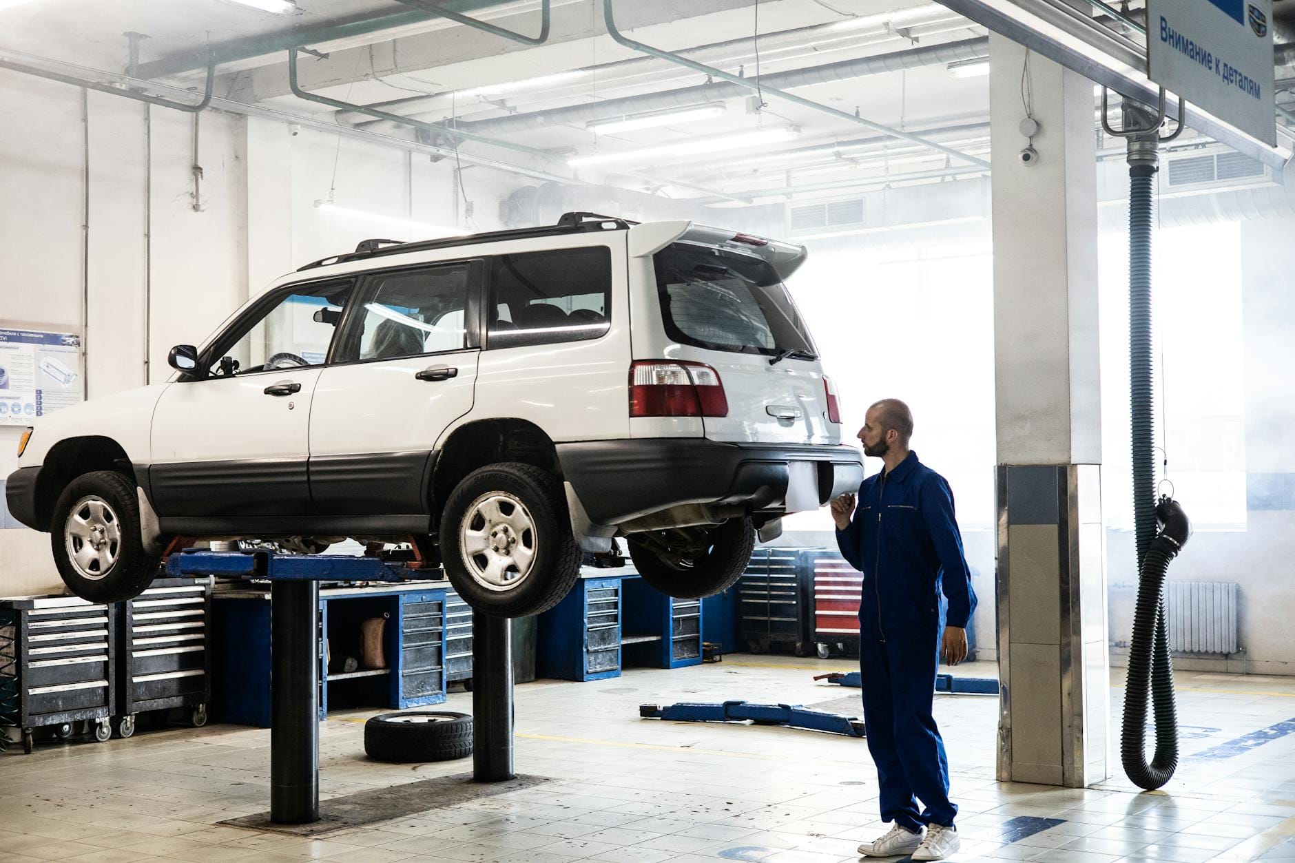 Jak kupić używane Subaru Forester: najczęstsze usterki, koszty napraw i punkty obowiązkowe przy oględzinach Mechanik ogląda podwozie podniesionego SUV-a w nowoczesnym warsztacie