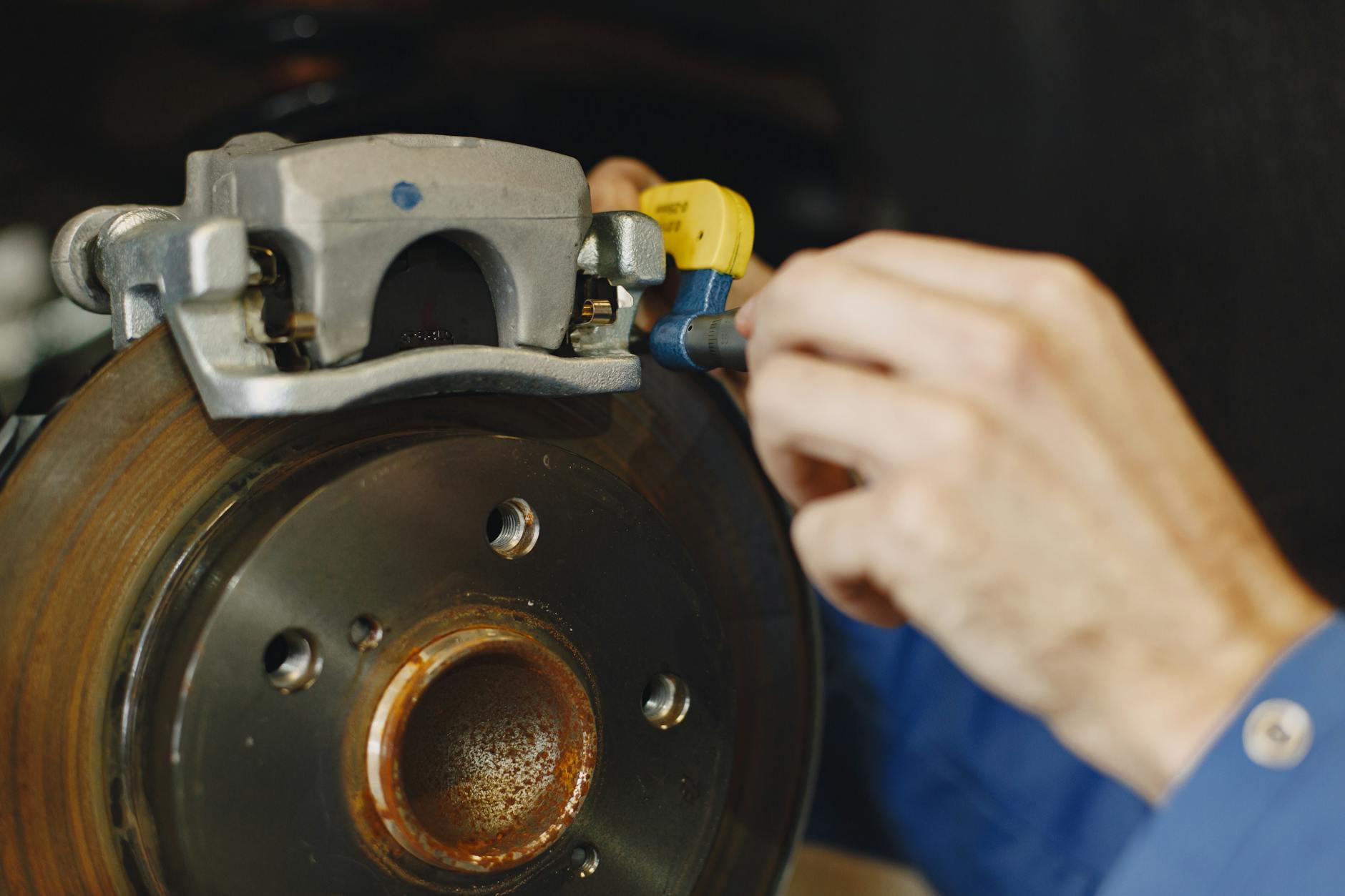 Mechanik sprawdza tarczę i klocki hamulcowe w samochodzie Renault Mechanik sprawdza tarczę i klocki hamulcowe w samochodzie Renault