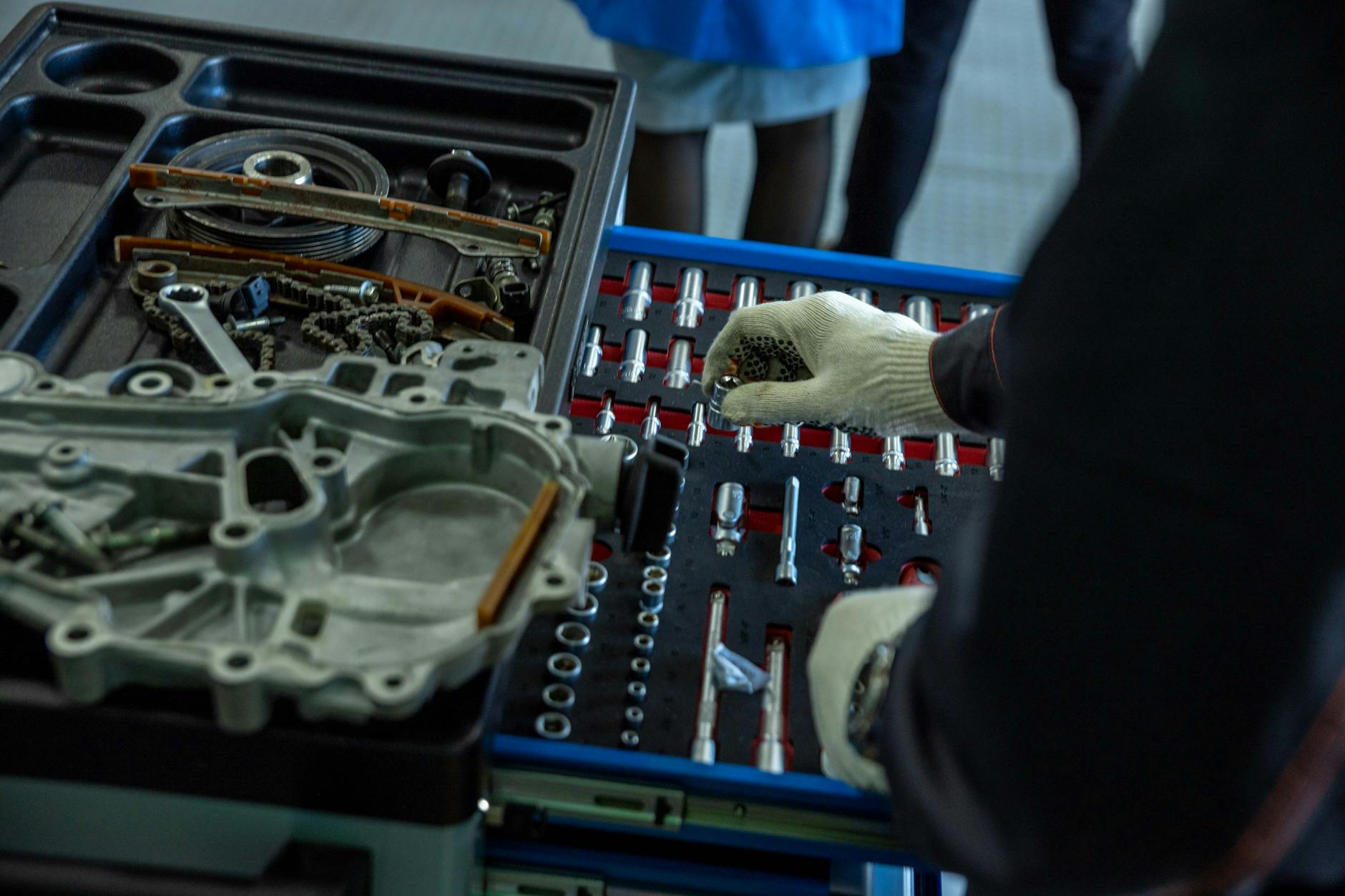 Mechanik w rękawicach porządkuje części i narzędzia w warsztacie