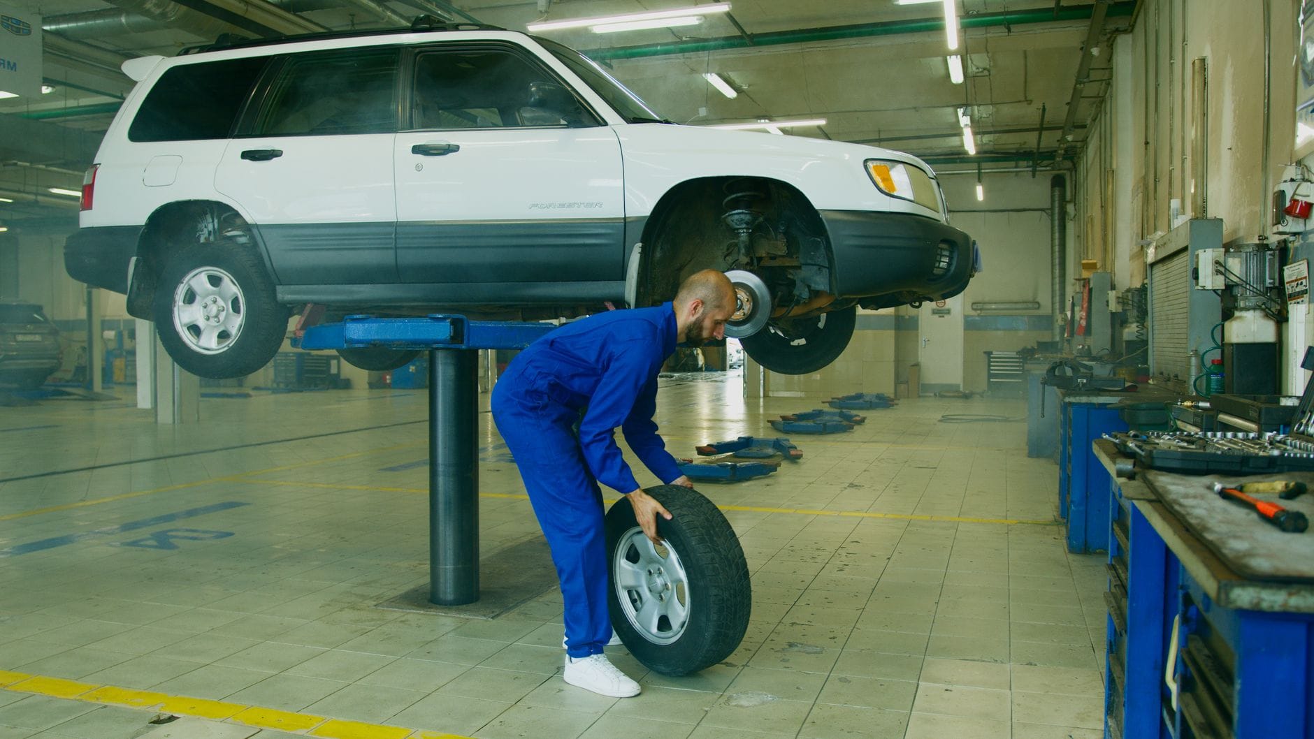 Mechanik wymienia koło w podniesionym SUV-ie w warsztacie samochodowym