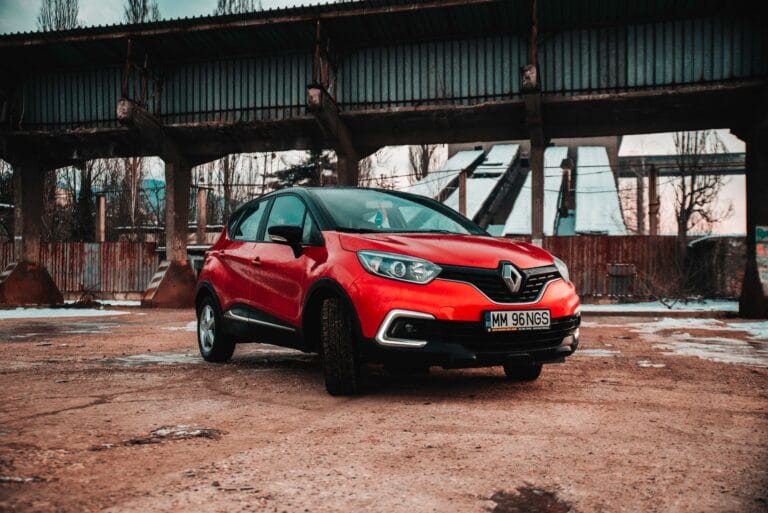 Czerwony Renault Captur zaparkowany pod wiaduktem w przemysłowym otoczeniu