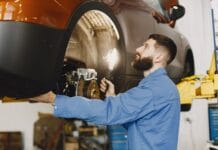 Klocki hamulcowe do Renault: oryginalne czy zamienniki? Jak wybrać bez ryzyka Mechanik w niebieskim kombinezonie sprawdza hamulce samochodu w warsztacie